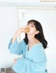 A woman in a blue sweater eating a donut.