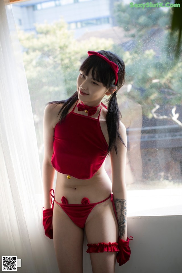 A woman in a red bikini standing by a window.