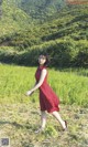 A woman in a red dress is walking through a field.