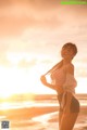 A woman standing on a beach next to the ocean.