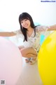 A young woman sitting on the floor with a bunch of balloons.