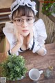 A woman wearing glasses sitting at a table with a cup of coffee.