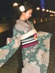 A woman in a kimono walking down a street at night.