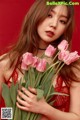 A woman in a red dress holding a bunch of pink tulips.