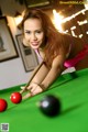 A woman in a bikini playing pool. 