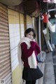 A woman standing in front of a building wearing a scarf.