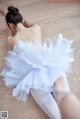 A woman in a white tutu sitting on the floor.