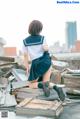 A woman in a school uniform sitting on top of a pile of rubble.