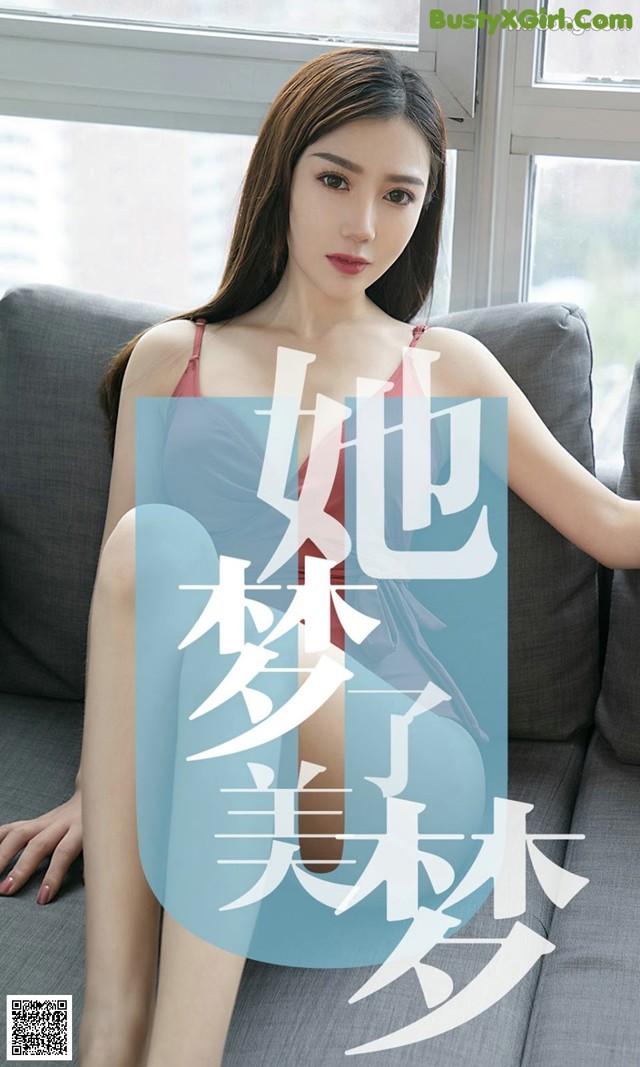 A woman sitting on a couch in a blue dress.