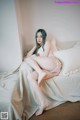 A woman sitting on a bed wearing a white lingerie.