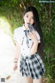 A woman in a school uniform holding a lollipop.