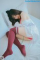 A woman in a white shirt and red stockings laying on a bed.